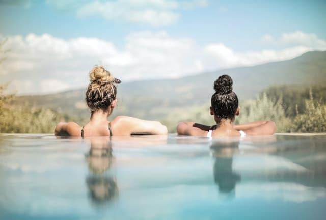 An image of two best friends sitting in a hot tub looking out at the mountains