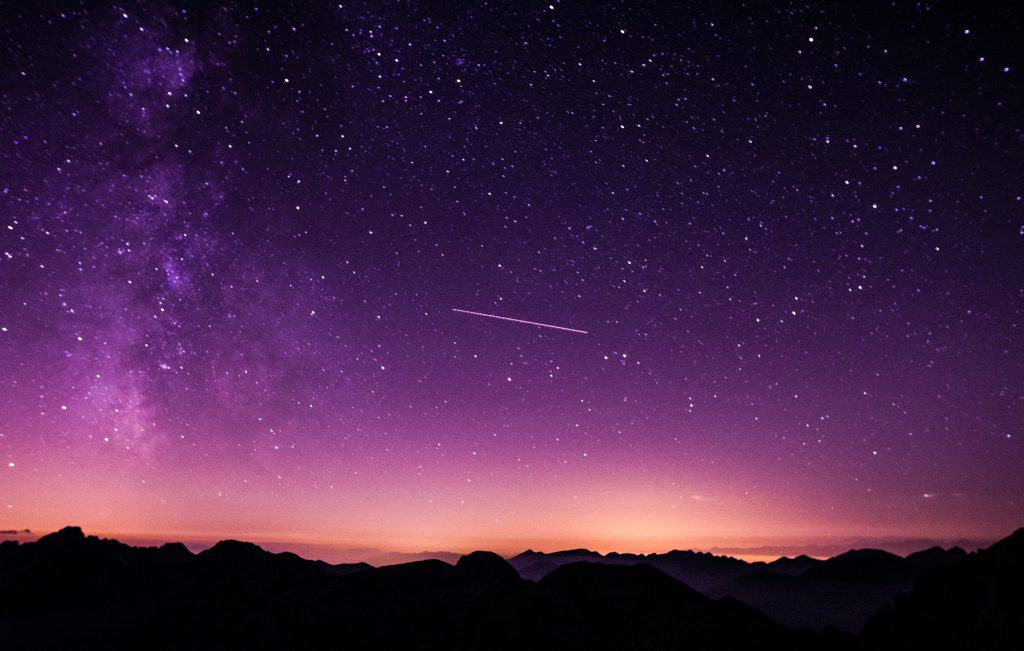 An image of space and stars over a mountain range.